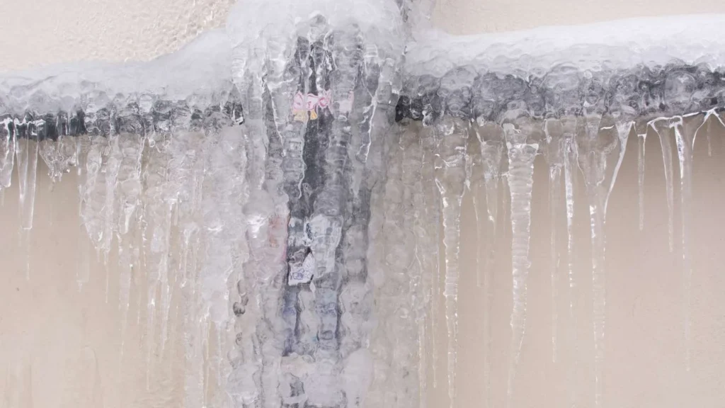 frozen water pipes with ice buildup on exterior wall during winter